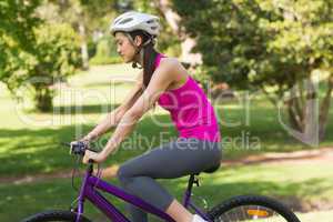Fit woman with helmet riding bicycle at park