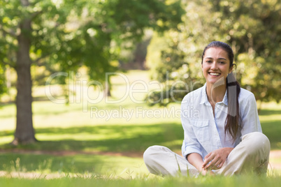 Smiling young woman sitting on grass in park