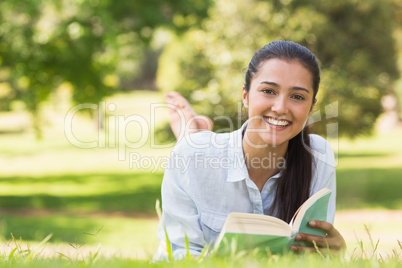 Portrait of a smiling woman reading book in park