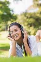 Cheerful young woman enjoying music in park