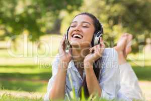 Cheerful young woman enjoying music in park