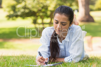 Concentrated woman with book and pen in park