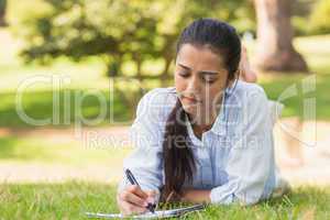 Concentrated woman with book and pen in park