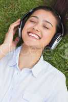 Cheerful young woman enjoying music in park