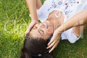 Cheerful young woman enjoying music in park