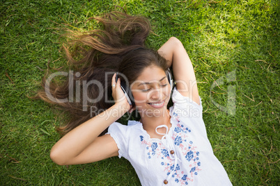 Cheerful young woman enjoying music in park