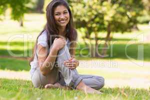 Full length portrait of smiling woman sitting in park