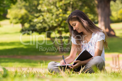 Young woman with book and pen in park