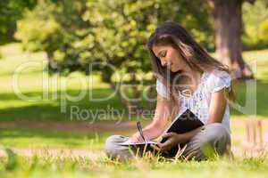 Young woman with book and pen in park