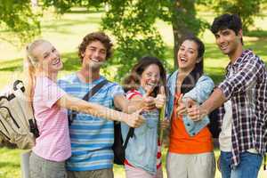 College friends gesturing thumbs up in campus