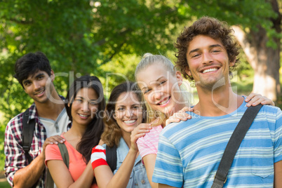 Happy college friends standing in row at campus