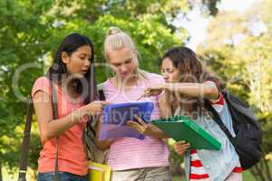 College friends looking at folder at campus