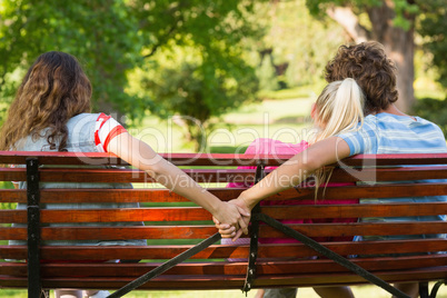 Man with girlfriend while holding hands with another woman