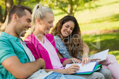 Happy college friends sitting on campus bench