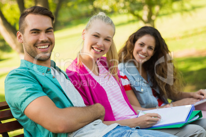 Happy college friends sitting on campus bench