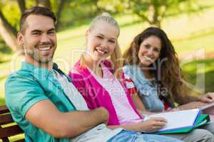 Happy college friends sitting on campus bench