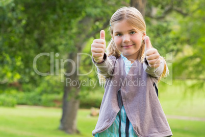 Cute young girl gesturing thumbs up at park