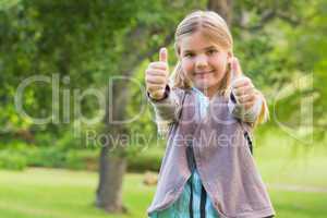Cute young girl gesturing thumbs up at park