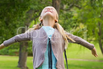 Girl with arms outstretched looking upwards at park