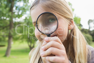 Young girl looking through magnifying glass at park