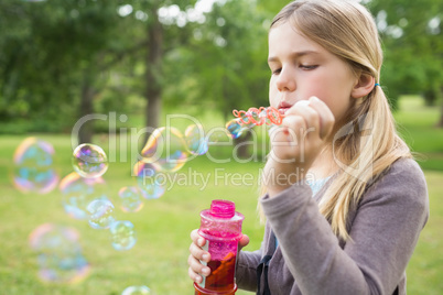 Girl blowing soap bubbles at park