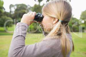 Girl looking through binoculars at park