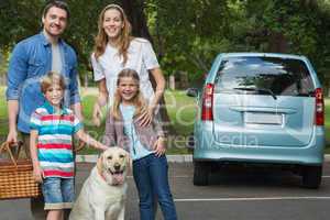 Happy family of four with car at picnic