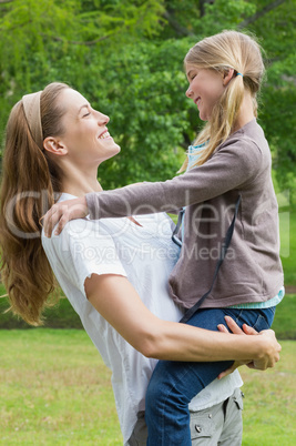 Smiling mother carrying daughter at park