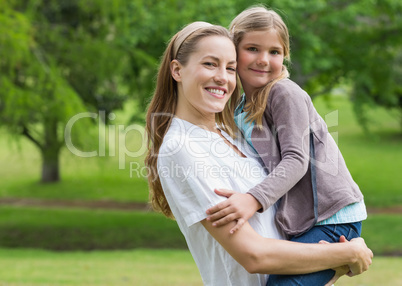 Smiling mother carrying daughter at park