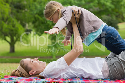 Smiling mother carrying daughter at park