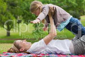 Smiling mother carrying daughter at park