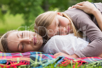 Relaxed mother and daughter lying at park