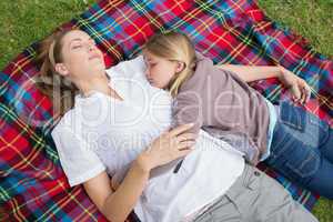 Relaxed mother and daughter lying at park