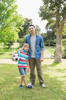 Smiling father and son with ball at park