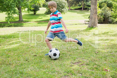 Full length of a boy kicking ball at park
