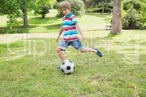 Full length of a boy kicking ball at park