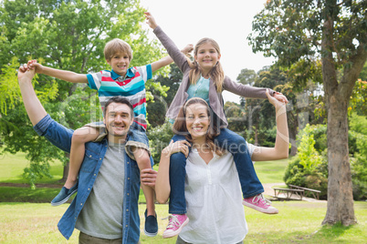 Parents carrying kids on shoulders at park