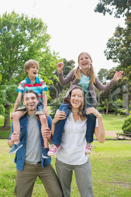 Happy parents carrying kids on shoulders at park