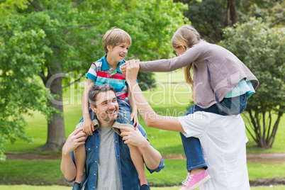 Parents carrying kids on shoulders at park