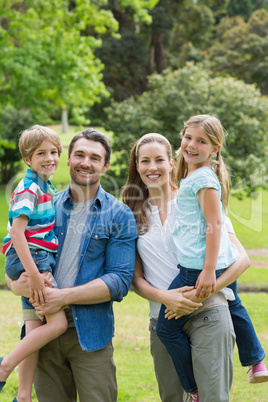 Happy parents carrying kids at park