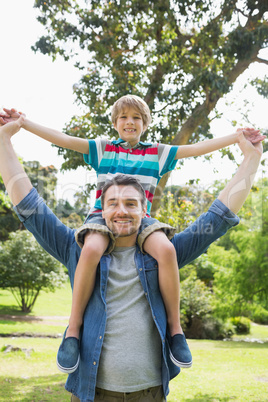 Father carrying boy on shoulders in park