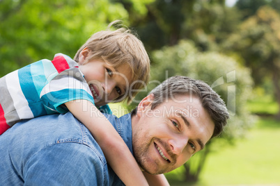 Father carrying young boy on back at park