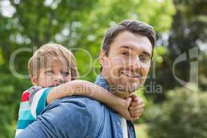 Father carrying young boy on back at park