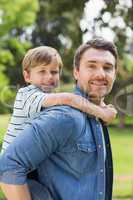 Portrait of father carrying boy on back at park