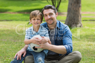 Portrait of father and son with ball at park