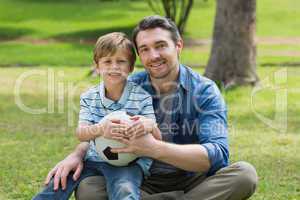 Portrait of father and son with ball at park