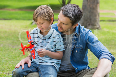 Boy with toy aeroplane sitting on father's lap