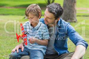 Boy with toy aeroplane sitting on father's lap