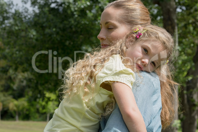 Mother carrying daughter at park