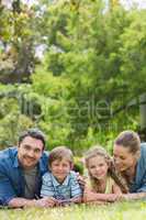 Happy parents and kids lying at park